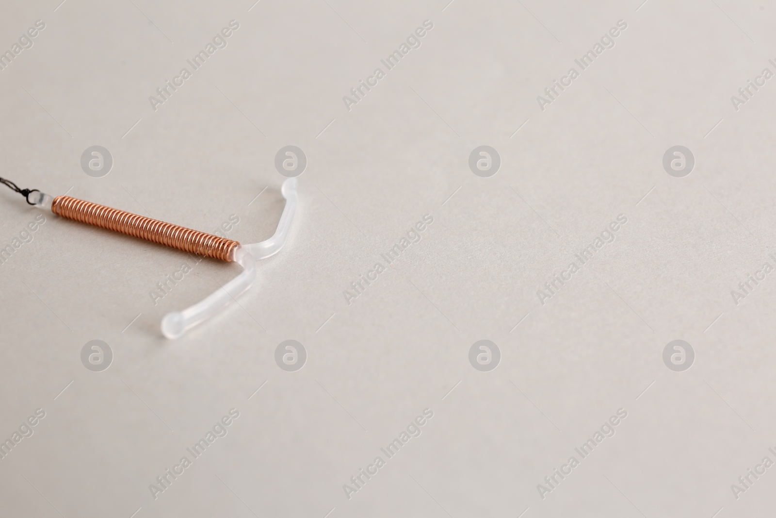 Photo of Copper intrauterine contraceptive device on light background. Space for text