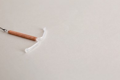Photo of Copper intrauterine contraceptive device on light background. Space for text