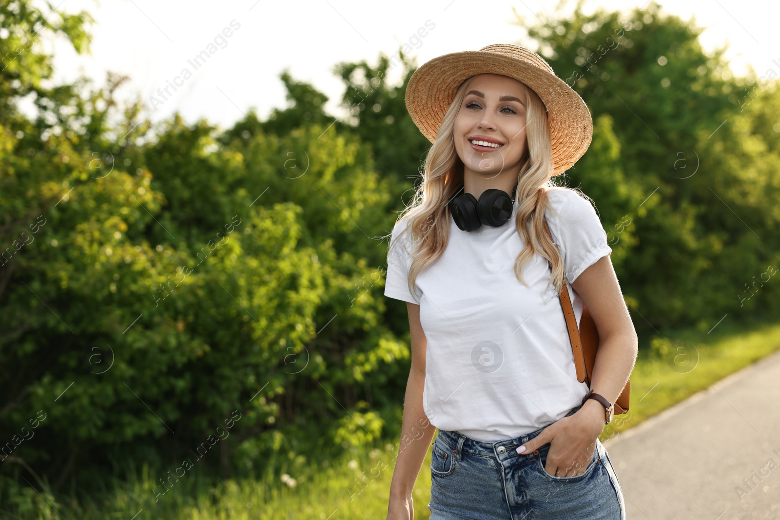 Photo of Happy young woman with headphones in park on spring day