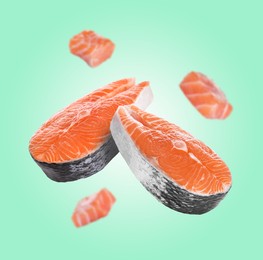 Image of Fresh salmon steaks and pieces falling on aquamarine background