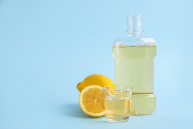 Photo of Mouthwash and fresh lemon on light blue background, space for text