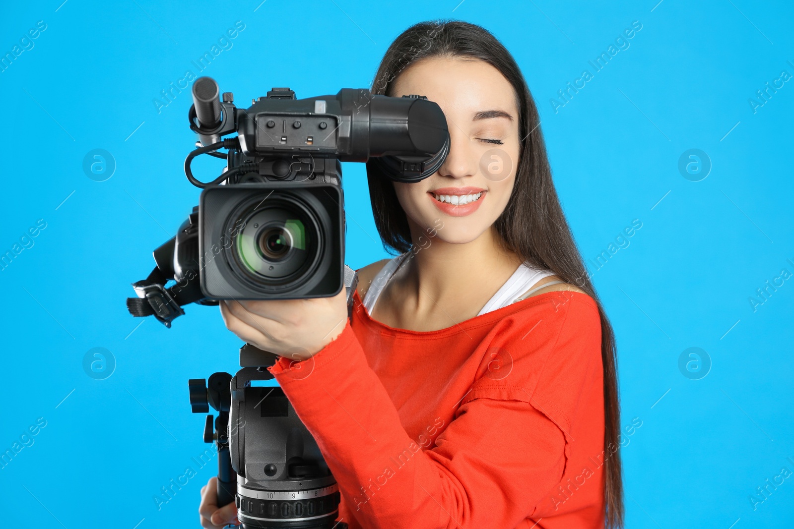 Photo of Operator with professional video camera on blue background