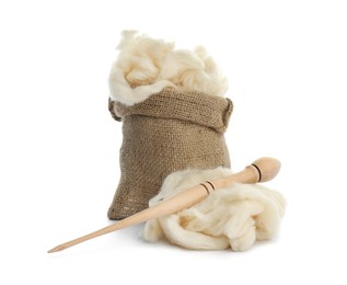 Photo of Soft wool in sack and spindle on white background