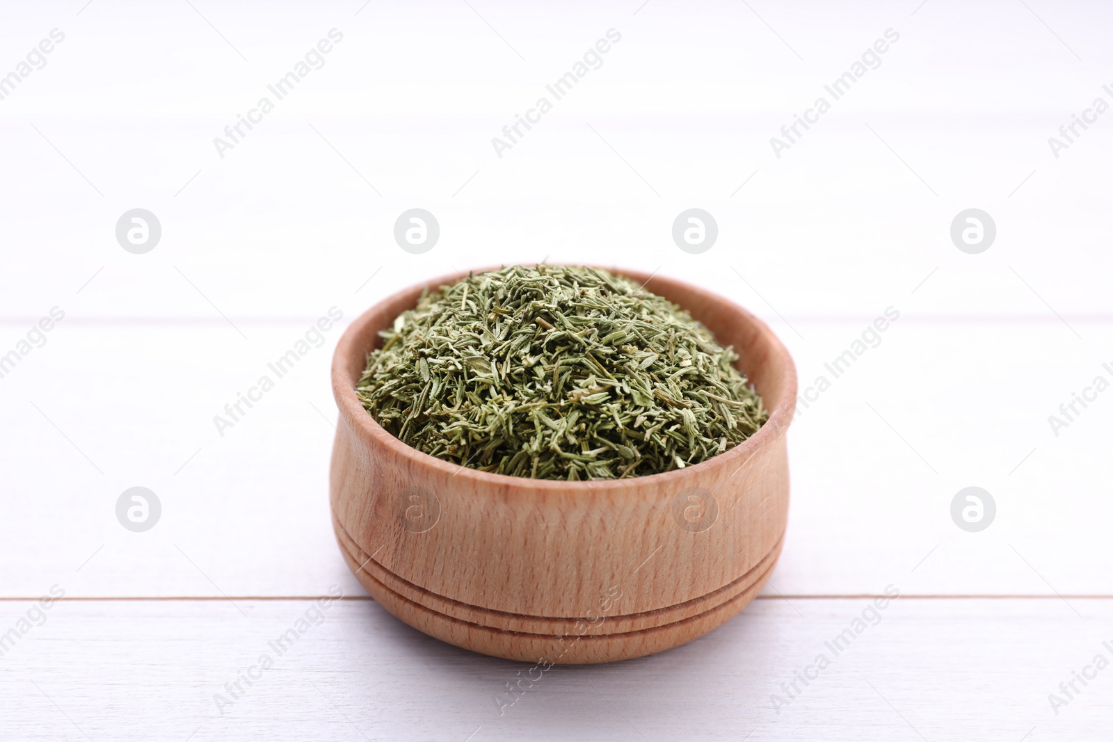 Photo of Bowl with dried thyme on white wooden table, closeup