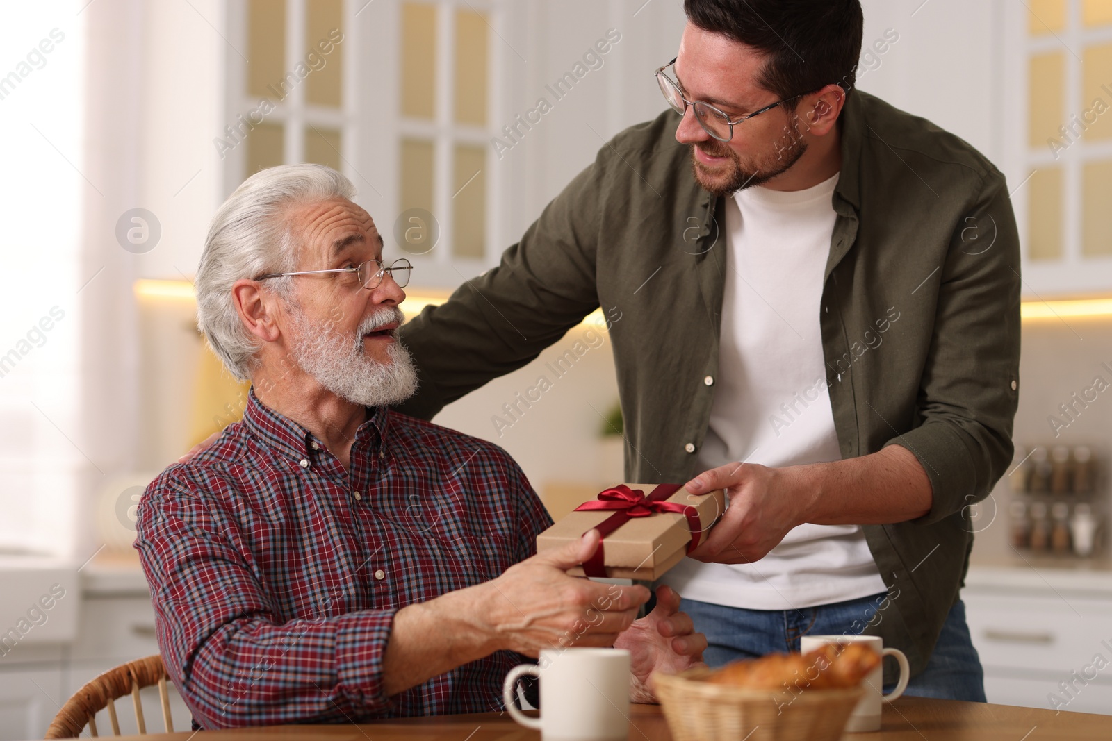 Photo of Son giving gift box to his dad at home