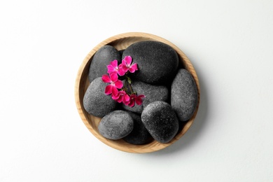 Photo of Spa stones and beautiful flowers on white table, top view