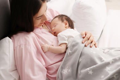 Mother with her sleeping newborn baby in bed