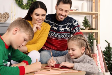 Photo of Cute children with their parents making beautiful Christmas greeting cards at home