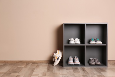 Photo of Modern cabinets with different sneakers near color wall, space for text