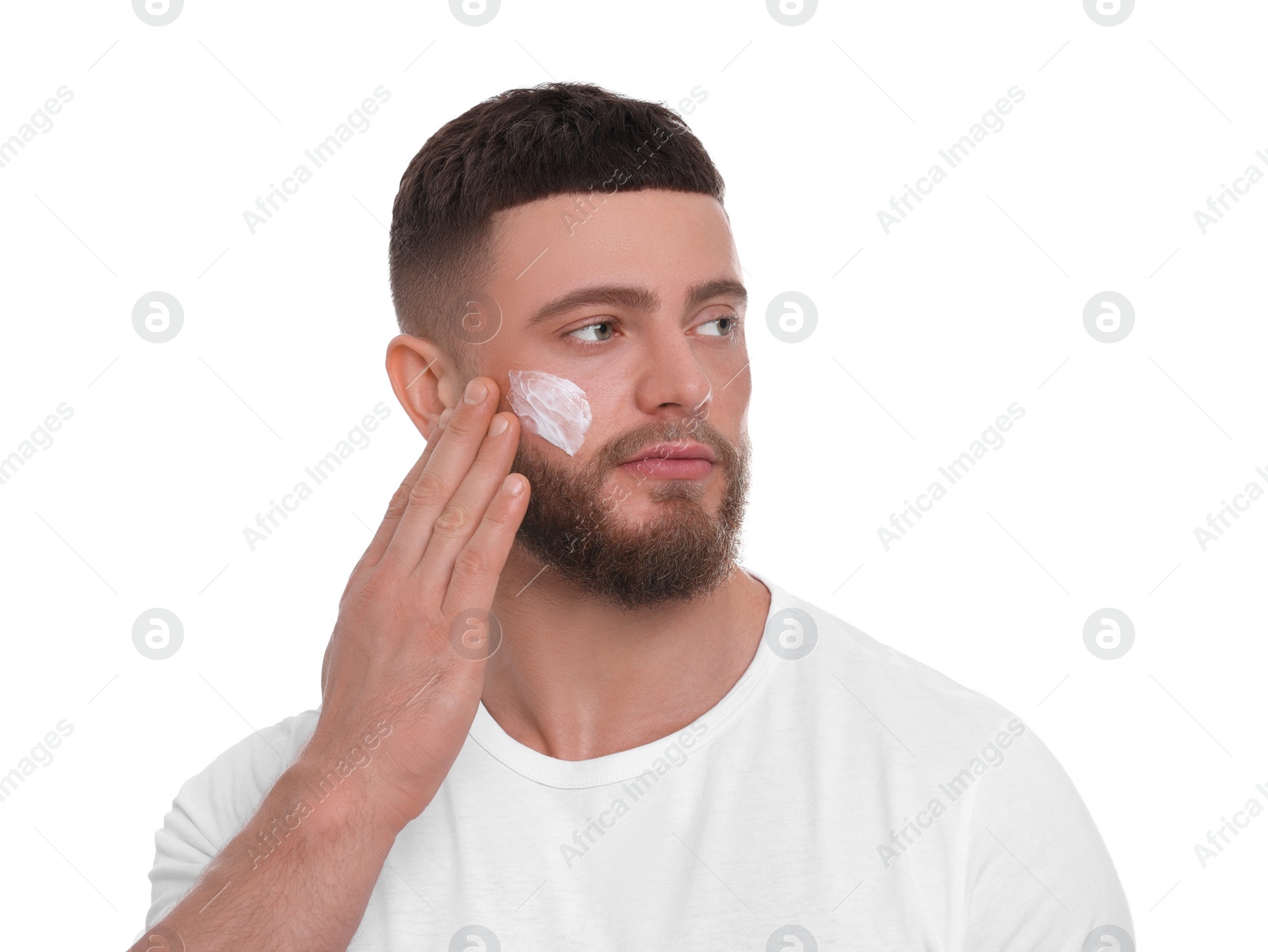 Photo of Handsome man applying cream onto his face on white background