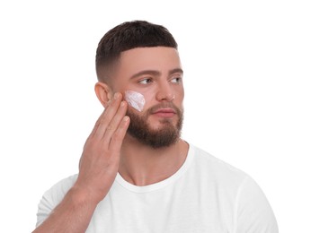 Handsome man applying cream onto his face on white background