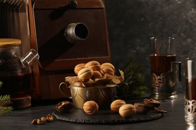 Photo of Aromatic walnut shaped cookies with tasty filling and tea on black table. Homemade pastry carrying nostalgic atmosphere