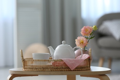 Cup of hot drink, teapot and beautiful eustoma flowers on table indoors, space for text