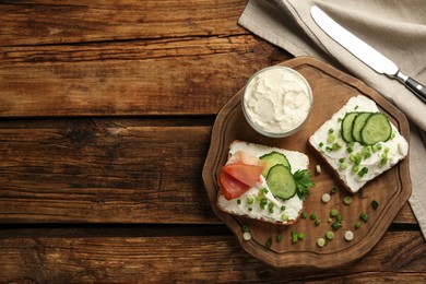 Delicious sandwiches with cream cheese and other ingredients on wooden table, flat lay. Space for text