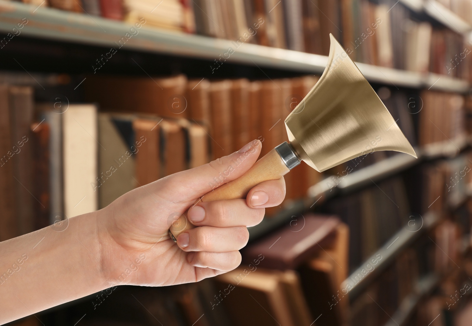 Image of Woman with school bell in library, closeup