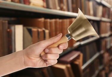 Image of Woman with school bell in library, closeup