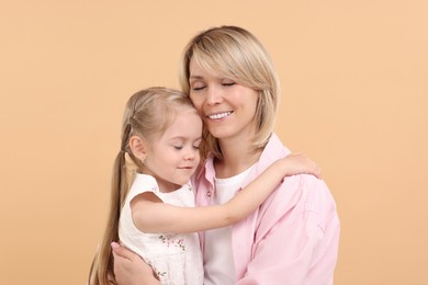 Photo of Daughter hugging her happy mother on beige background