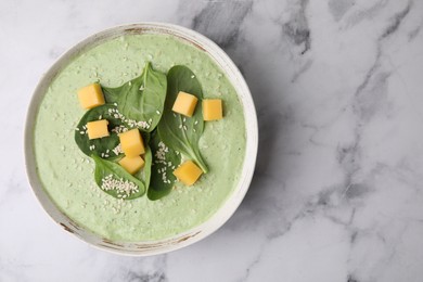 Photo of Delicious spinach cream soup with cheese and sesame seeds in bowl on white marble table, top view. Space for text