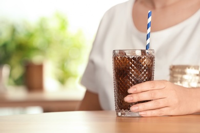 Woman with glass of tasty refreshing cola at table, closeup. Space for text