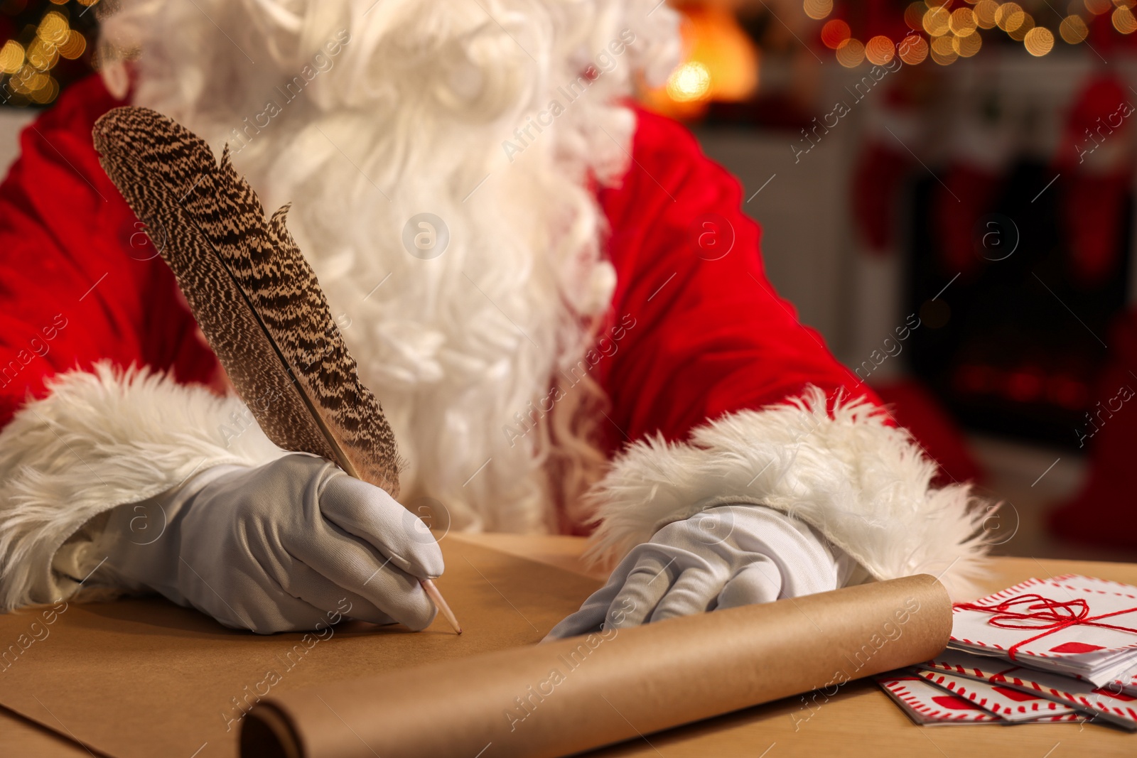 Photo of Merry Christmas. Santa Claus writing letter at table in room, closeup