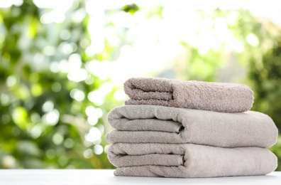 Stack of clean soft towels on table against blurred background. Space for text