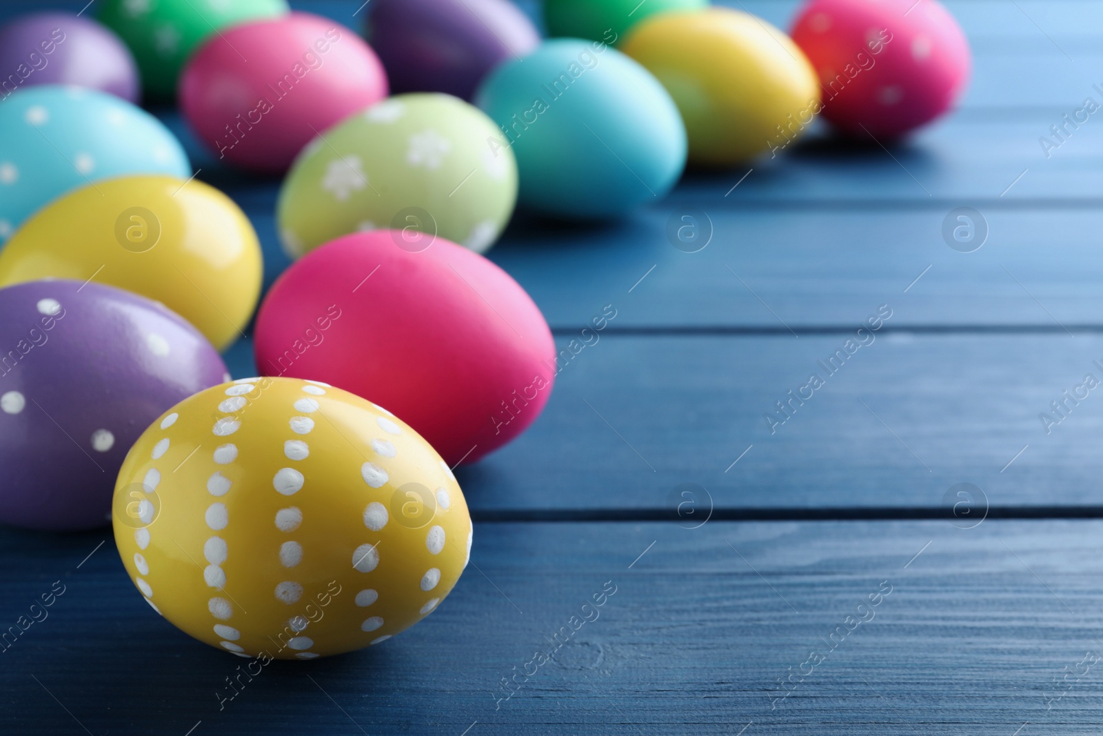 Photo of Colorful eggs on blue wooden background, closeup with space for text. Happy Easter