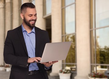 Lawyer with laptop near building outdoors, space for text