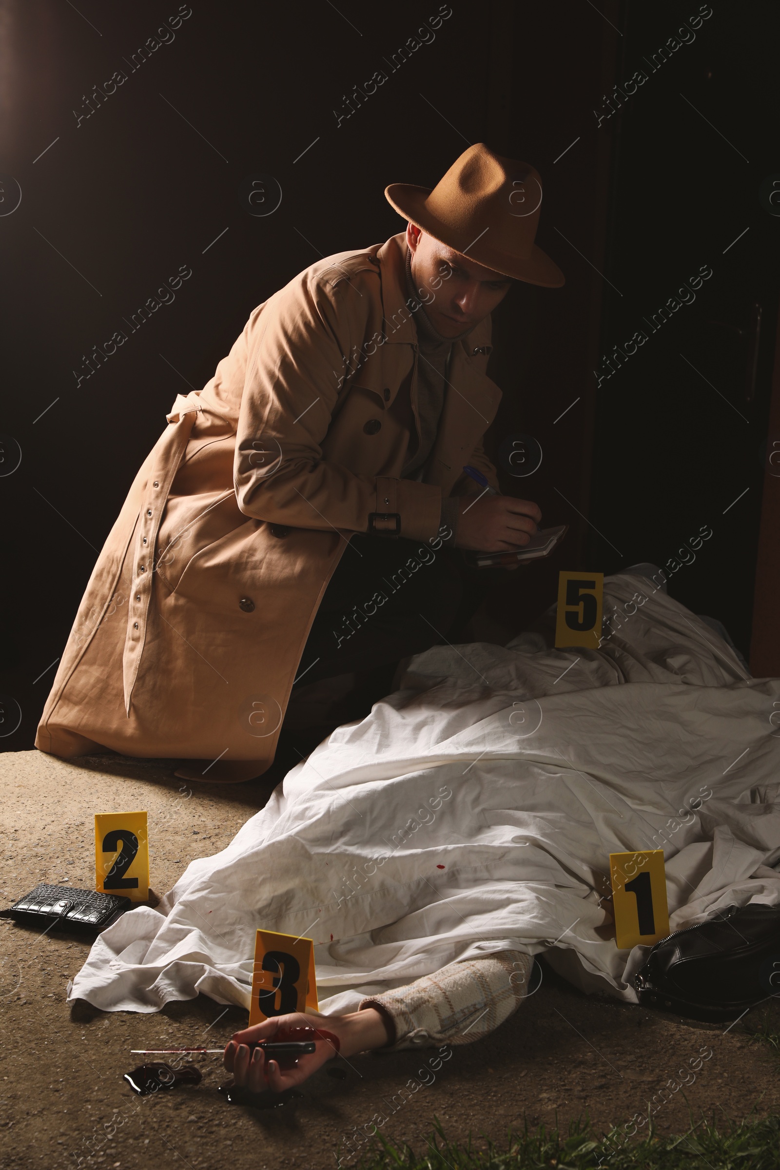 Photo of Investigator examining crime scene with dead body outdoors