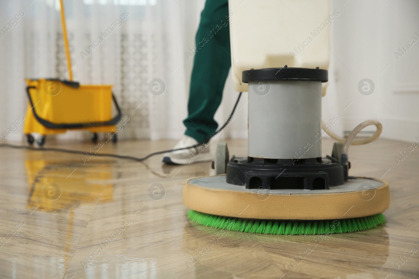 Photo of Professional janitor cleaning parquet floor with polishing machine indoors, closeup. Space for text