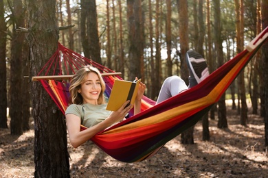 Woman with book relaxing in hammock outdoors on summer day