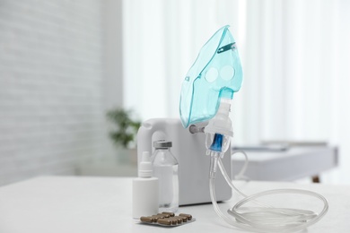 Photo of Modern nebulizer with face mask and medicines on white table indoors. Equipment for inhalation