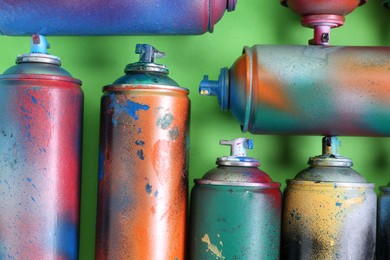 Photo of Many spray paint cans on green background, flat lay