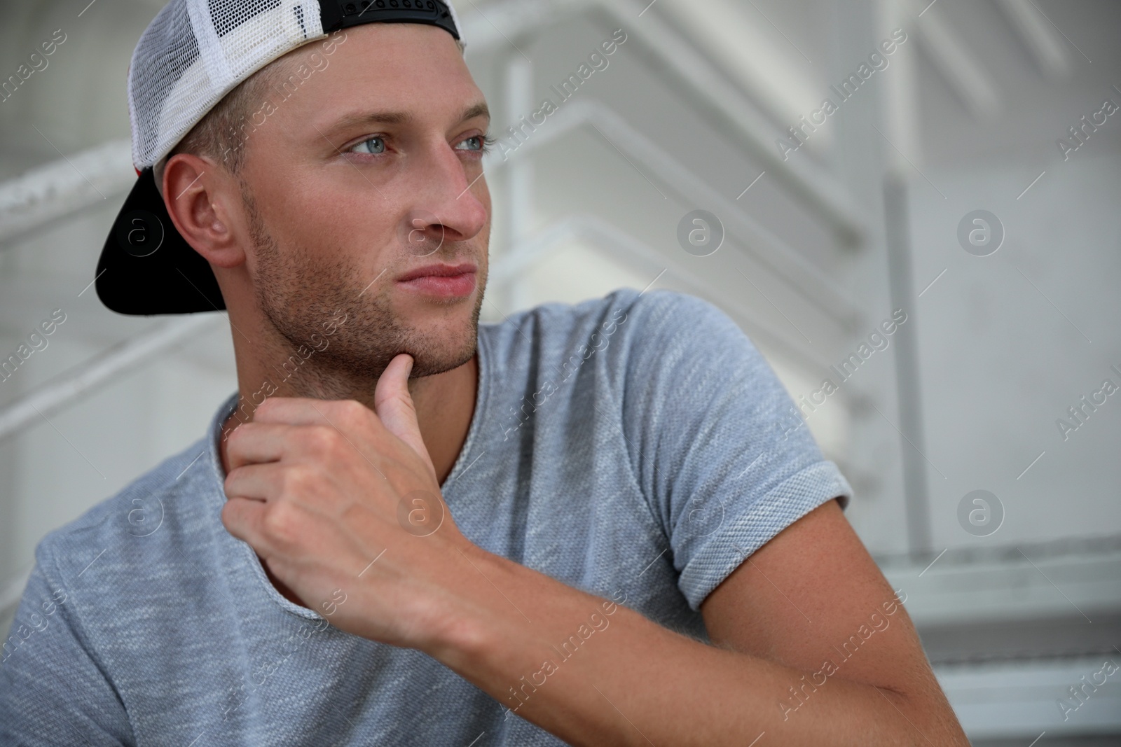 Photo of Handsome young man in stylish cap sitting on stairs