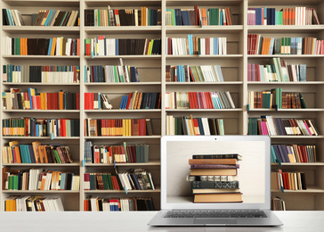 Image of Digital library concept. Modern laptop on table and shelves with books indoors