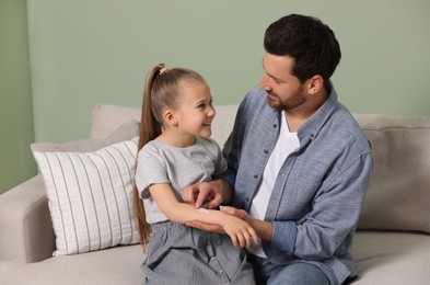 Photo of Father applying ointment onto his daughter's arm on couch