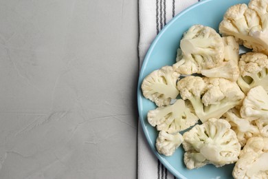 Photo of Plate with cut fresh raw cauliflower on light grey table, top view. Space for text