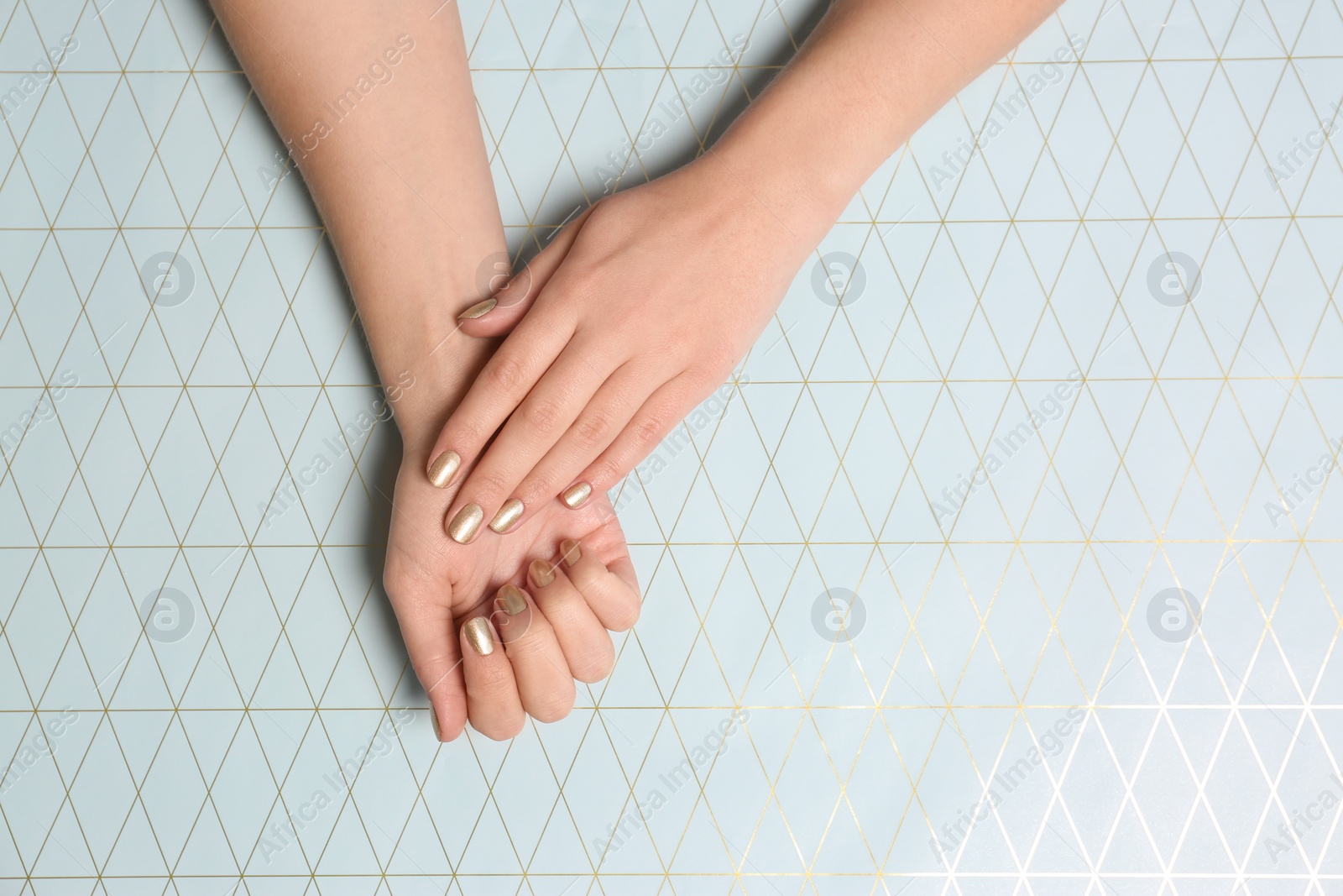 Photo of Woman showing golden manicure on color background, top view with space for text. Nail polish trends