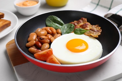 Photo of Tasty breakfast with cooked egg, beans and bacon on frying pan, closeup