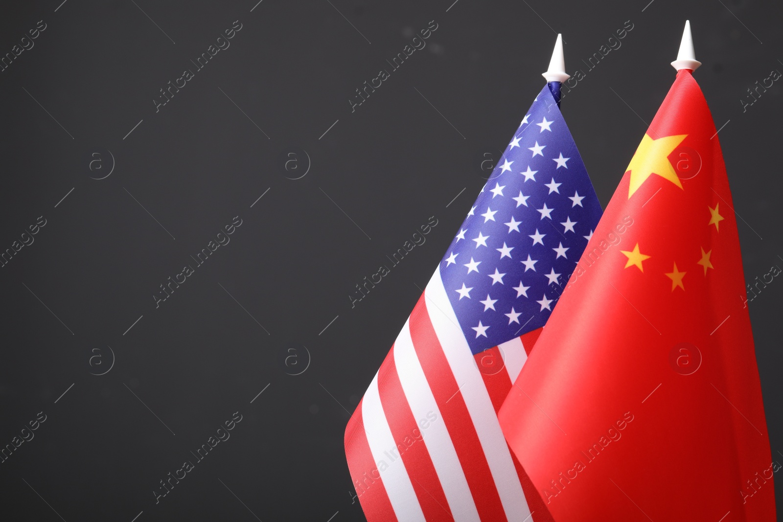 Photo of Closeup view of USA and China flags on dark background, space for text. International relations