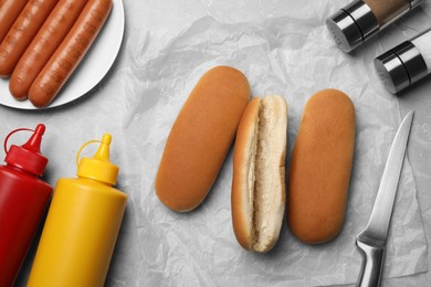 Different tasty ingredients for hot dog on light grey marble table, flat lay