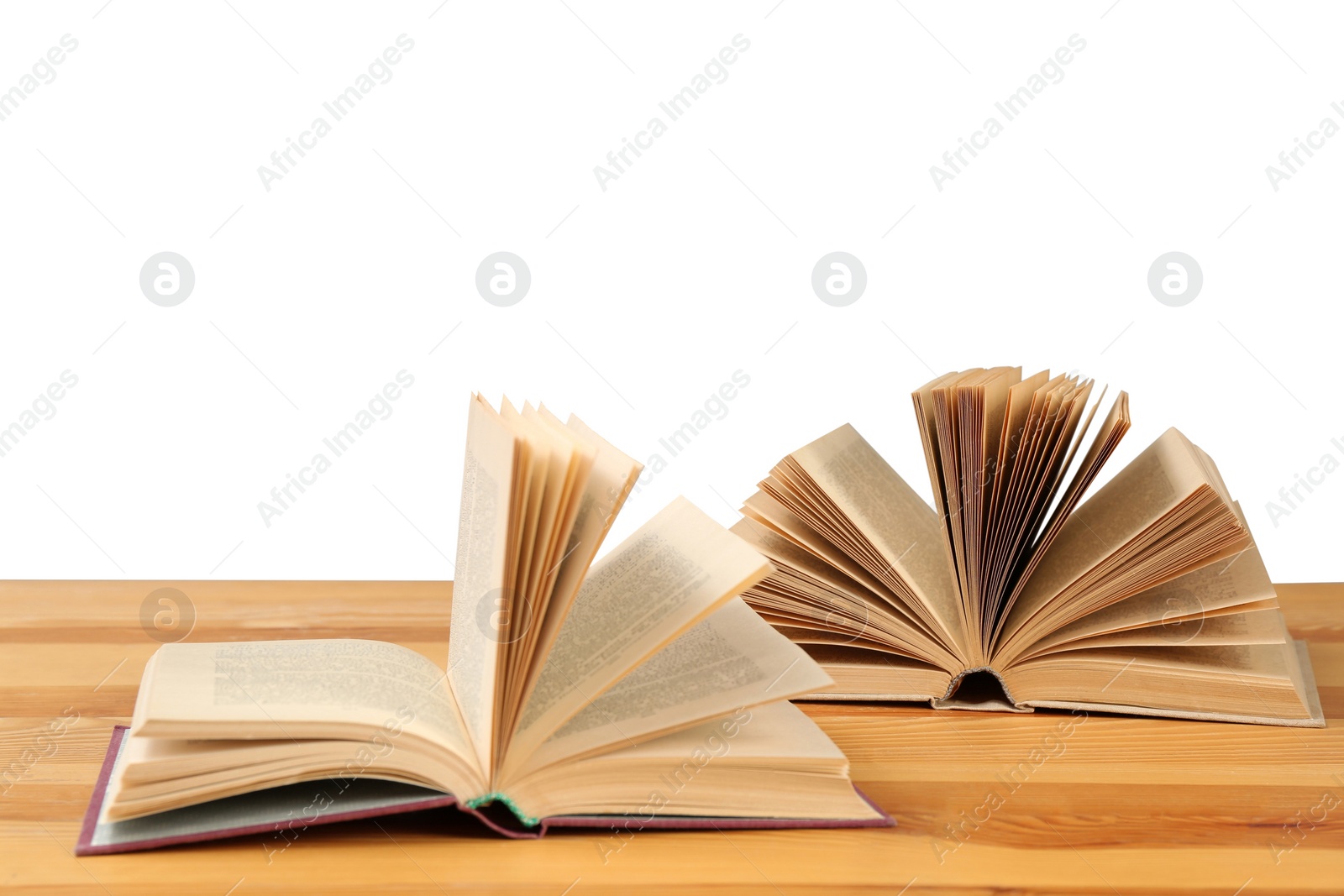 Photo of Open books on wooden table against white background. Library material