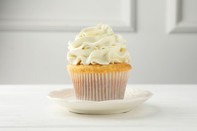 Photo of Tasty vanilla cupcake with cream on white table, closeup