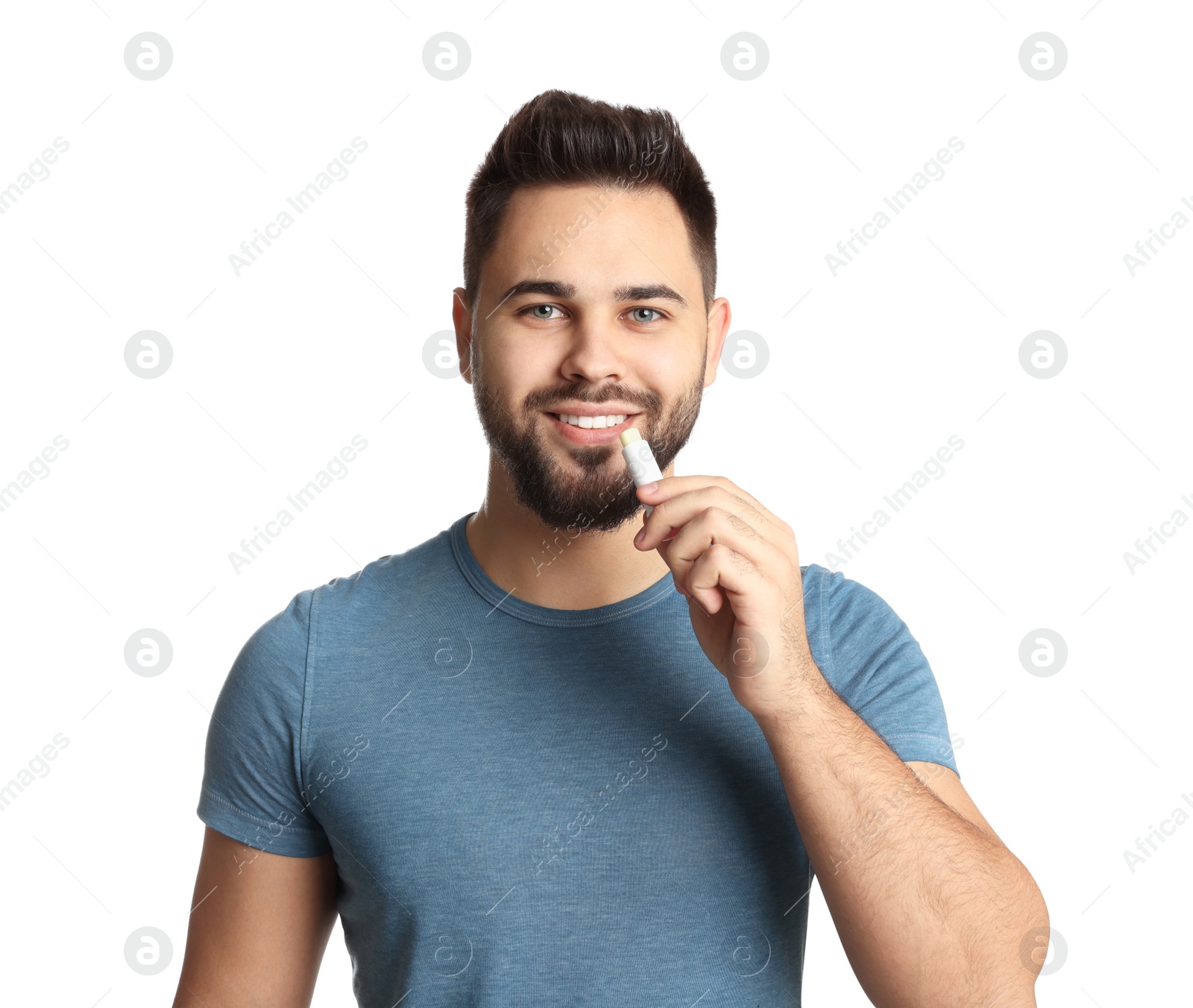 Photo of Young man applying lip balm on white background