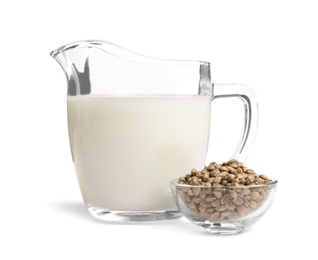 Photo of Bowl with hemp seeds and jug of milk on white background