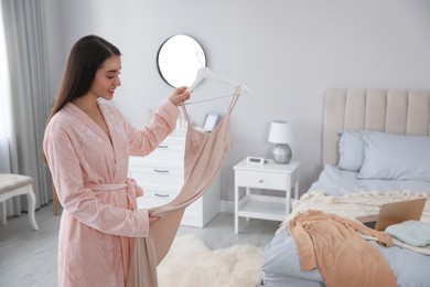 Young woman choosing clothes for work day at home. Morning routine