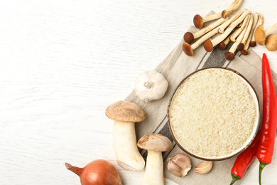 Flat lay composition with different ingredients on white wooden table, space for text. Risotto recipe