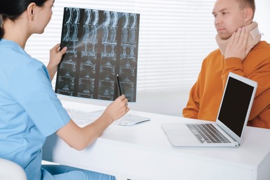 Doctor with neck MRI image consulting patient in clinic, closeup