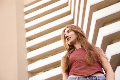 Beautiful young woman at modern building, low angle view