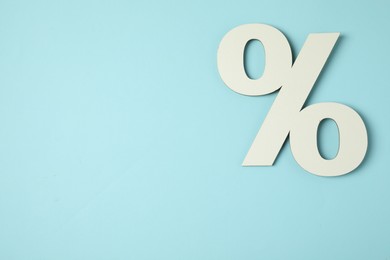 Photo of White percent sign on light blue background, top view. Space for text