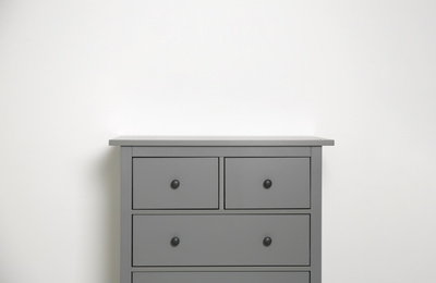 Photo of Grey chest of drawers on light background